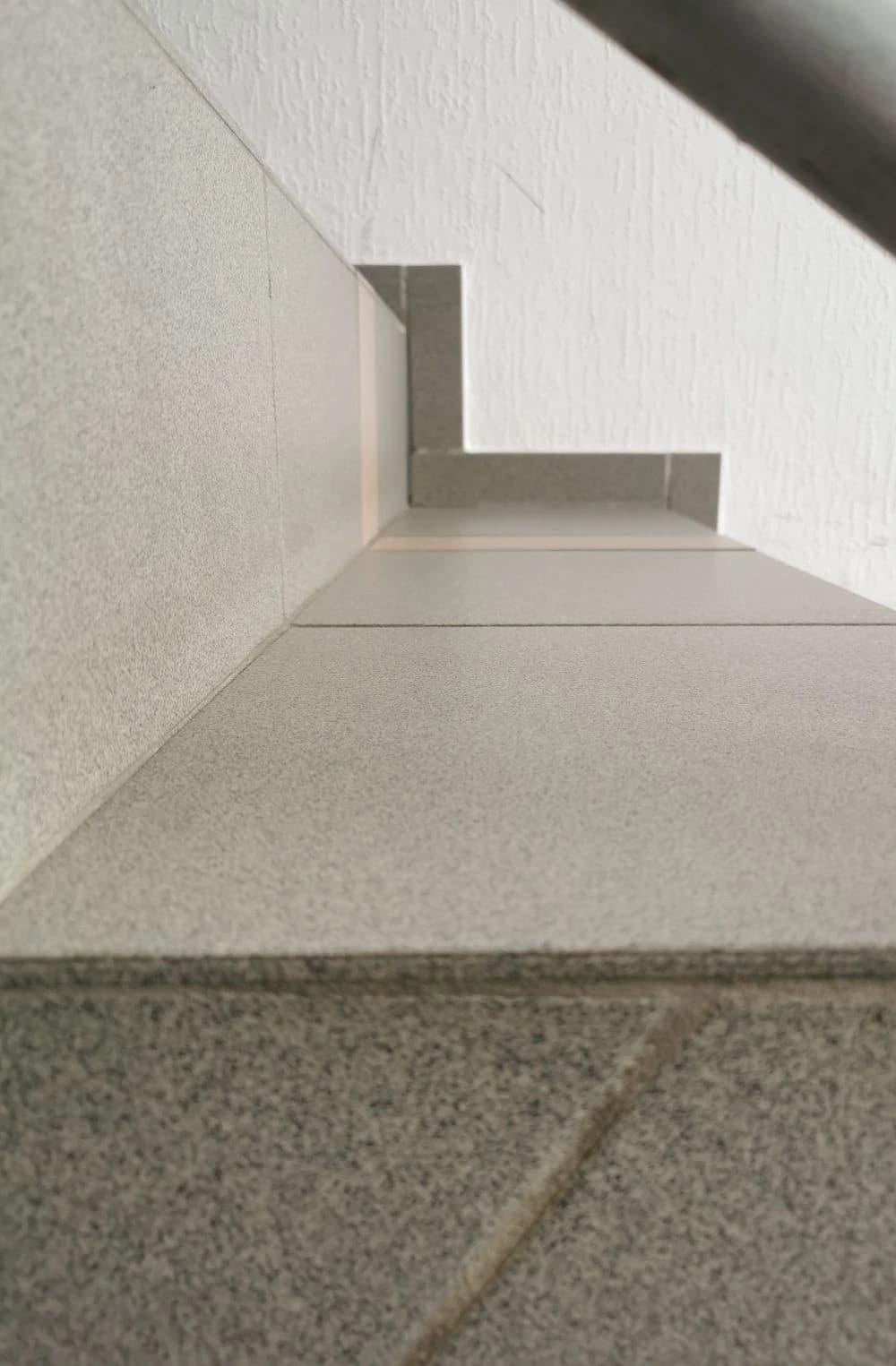 Nahaufnahme einer Treppe mit grauen Fliesen. Die Perspektive zeigt die Stufen von unten nach oben.